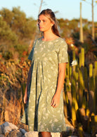 Setting-sun drenched image of model in cotton relaxed fit dress with short sleeves and high round neckline