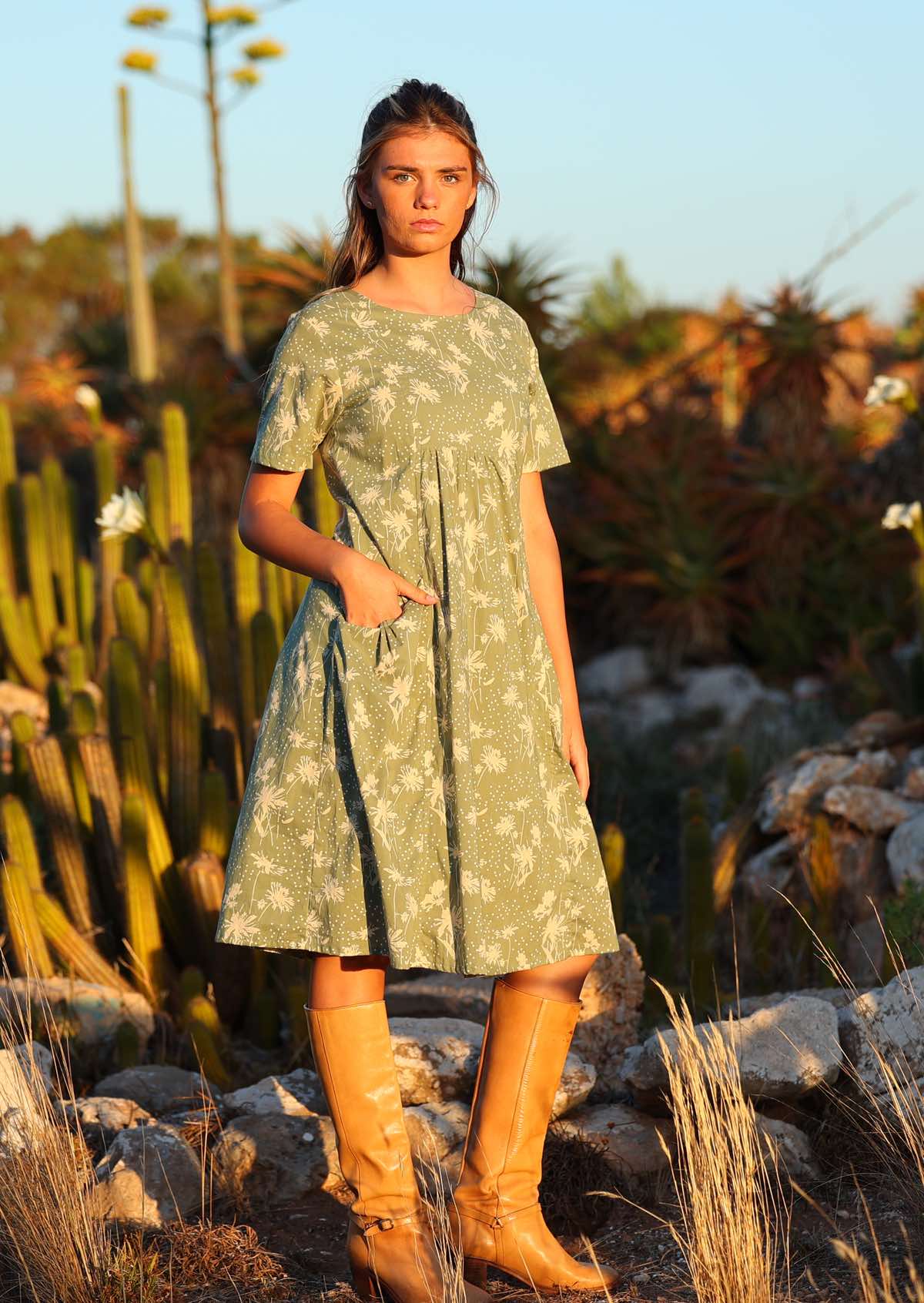 Setting-sun drenched photo of model in cotton over the knee dress in floral on pale green base print