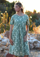 Woman wears cotton relaxed fit dress with round neckline and short sleeves in cream floral on pale green print