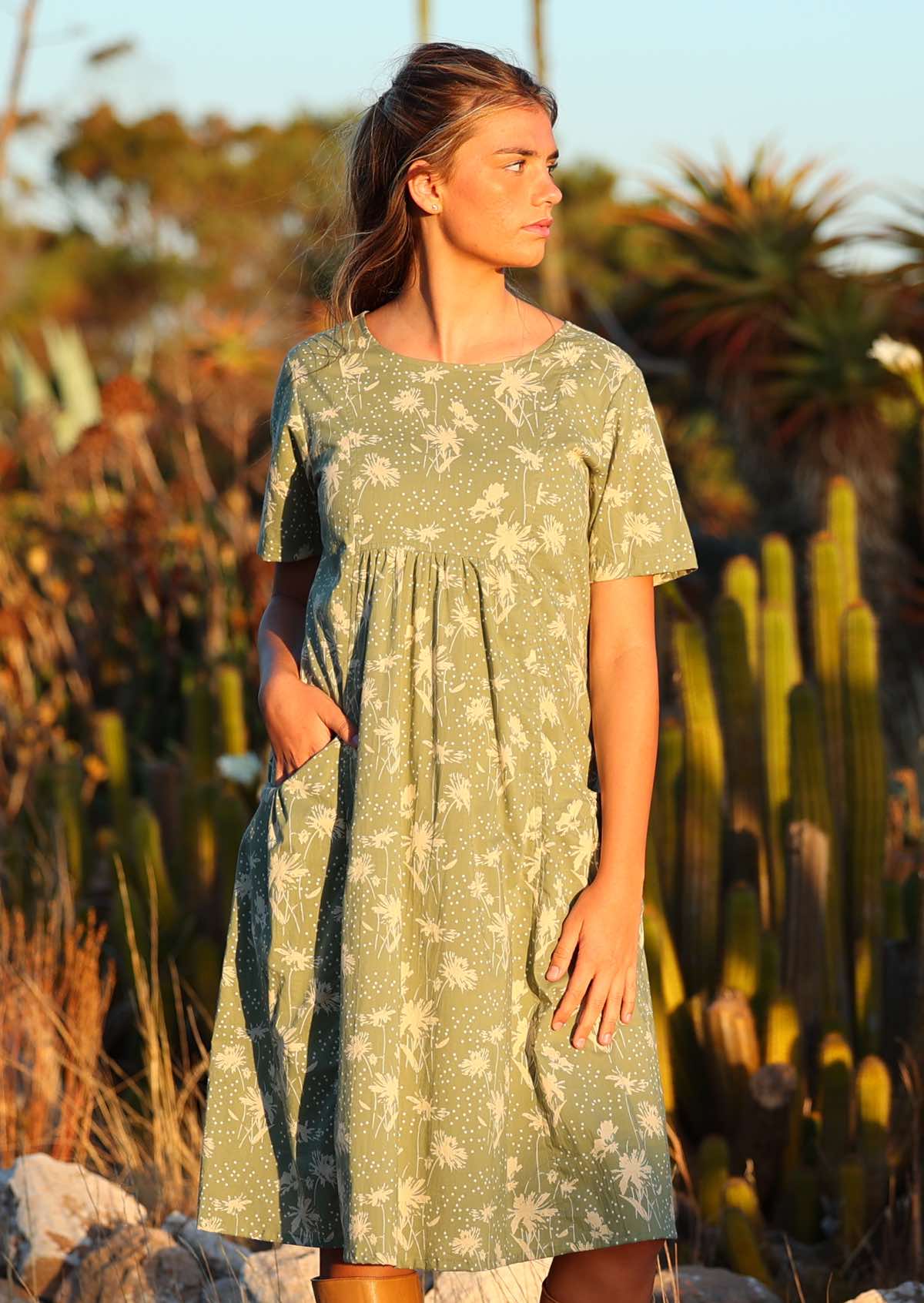 Setting-sun drenched photo of model in cotton relaxed fit dress with hand in pocket