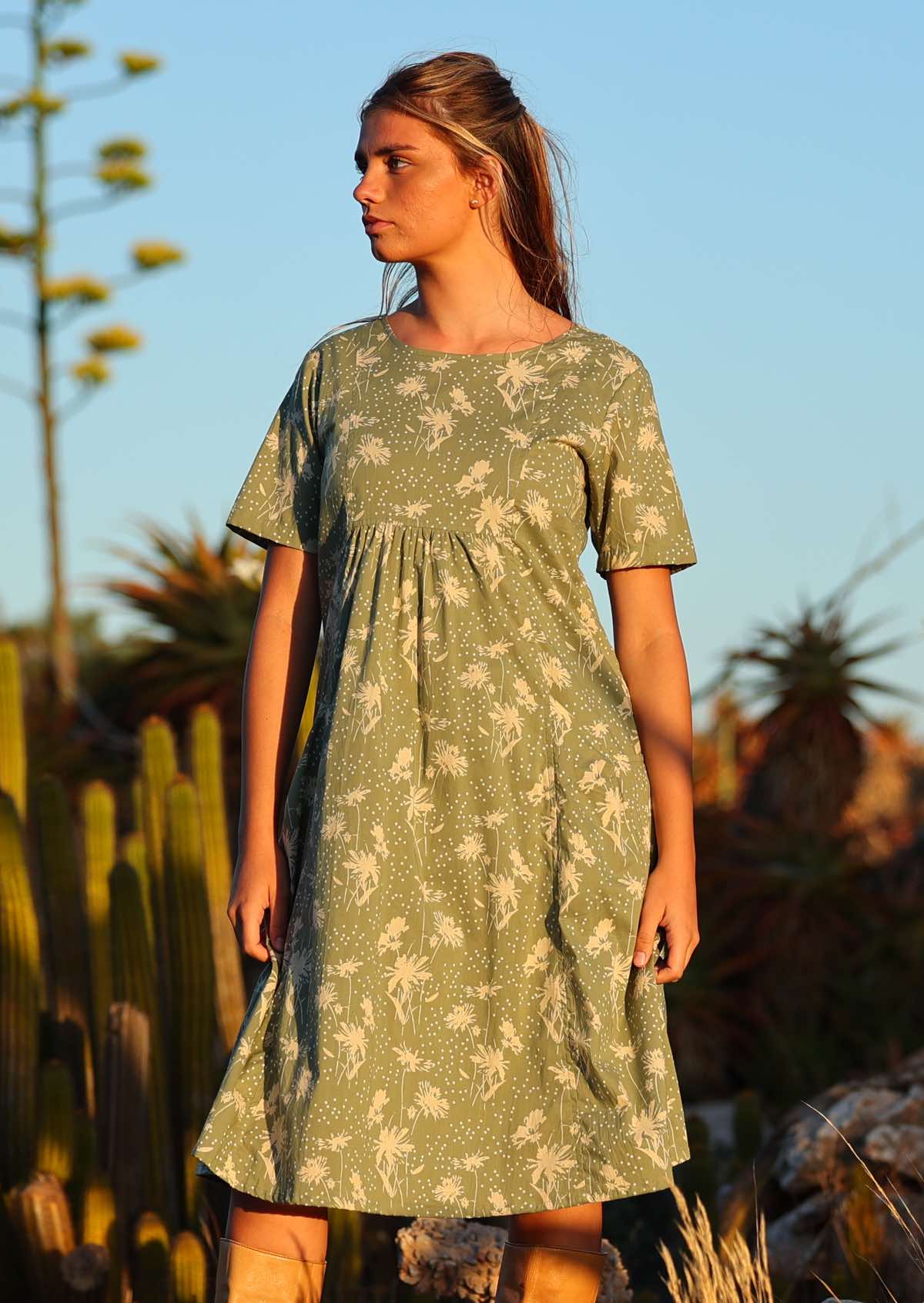 Setting-sun drenched photo of model in loose fit cotton dress with gathers under the bust and short sleeves