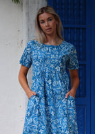 Close up of woman in cotton relaxed fit dress with round neckline and hands in pockets