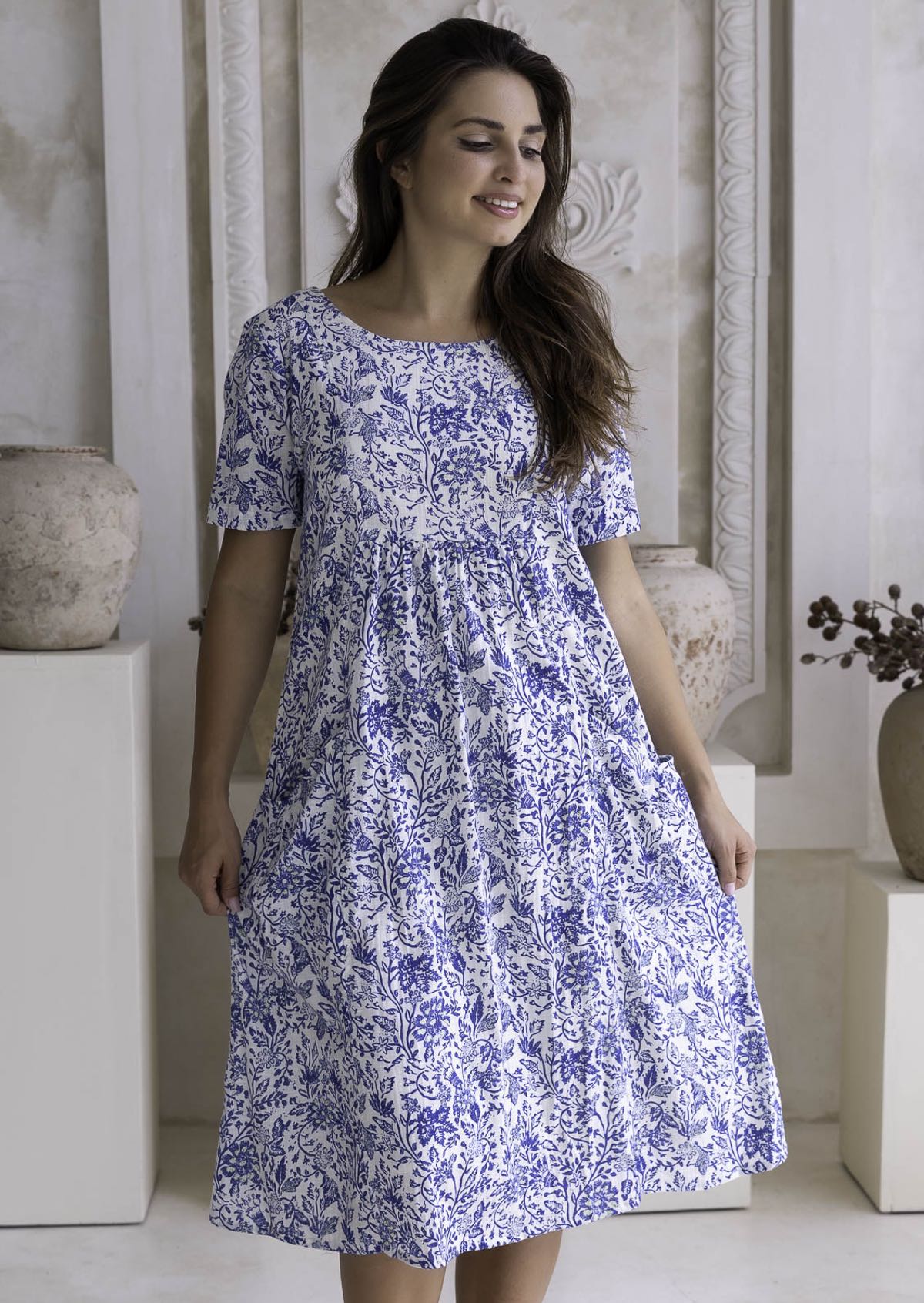 Woman wearing a blue floral cotton dress which sits below the knee.