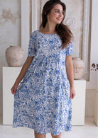 Woman wearing a blue floral cotton dress, 100% cotton, knee length, relaxed fit.