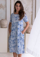 Woman wearing a blue floral cotton dress with her hand in pocket.