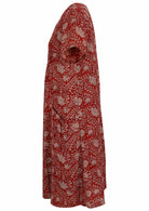 Side view of cotton dress with round neckline and short sleeves in red based floral print. 