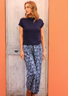 Model standing wearing Greta Pant Neela navy 100 percent cotton relaxed fit pants paired with navy top and tan leather ankle boots