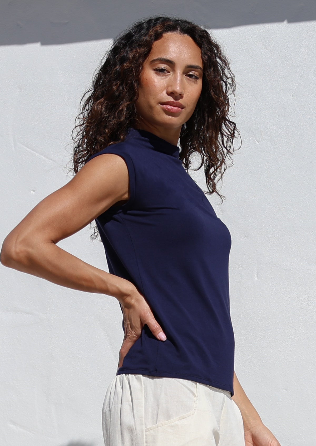 Woman wearing a navy sleeveless top against a white background