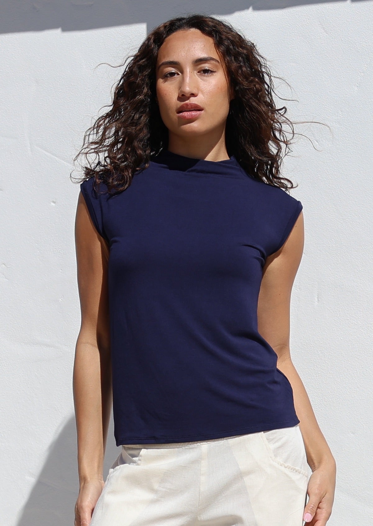 Woman wearing a navy sleeveless top against a white background