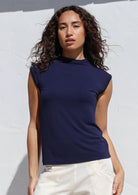 Woman wearing a navy sleeveless top against a white background