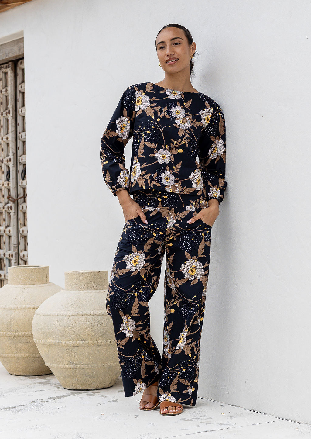 The model wears a matching Camellia print top and high waisted wide leg cotton pants in black based floral print