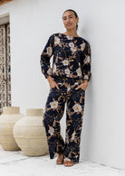 The model wears a matching Camellia print top and high waisted wide leg cotton pants in black based floral print