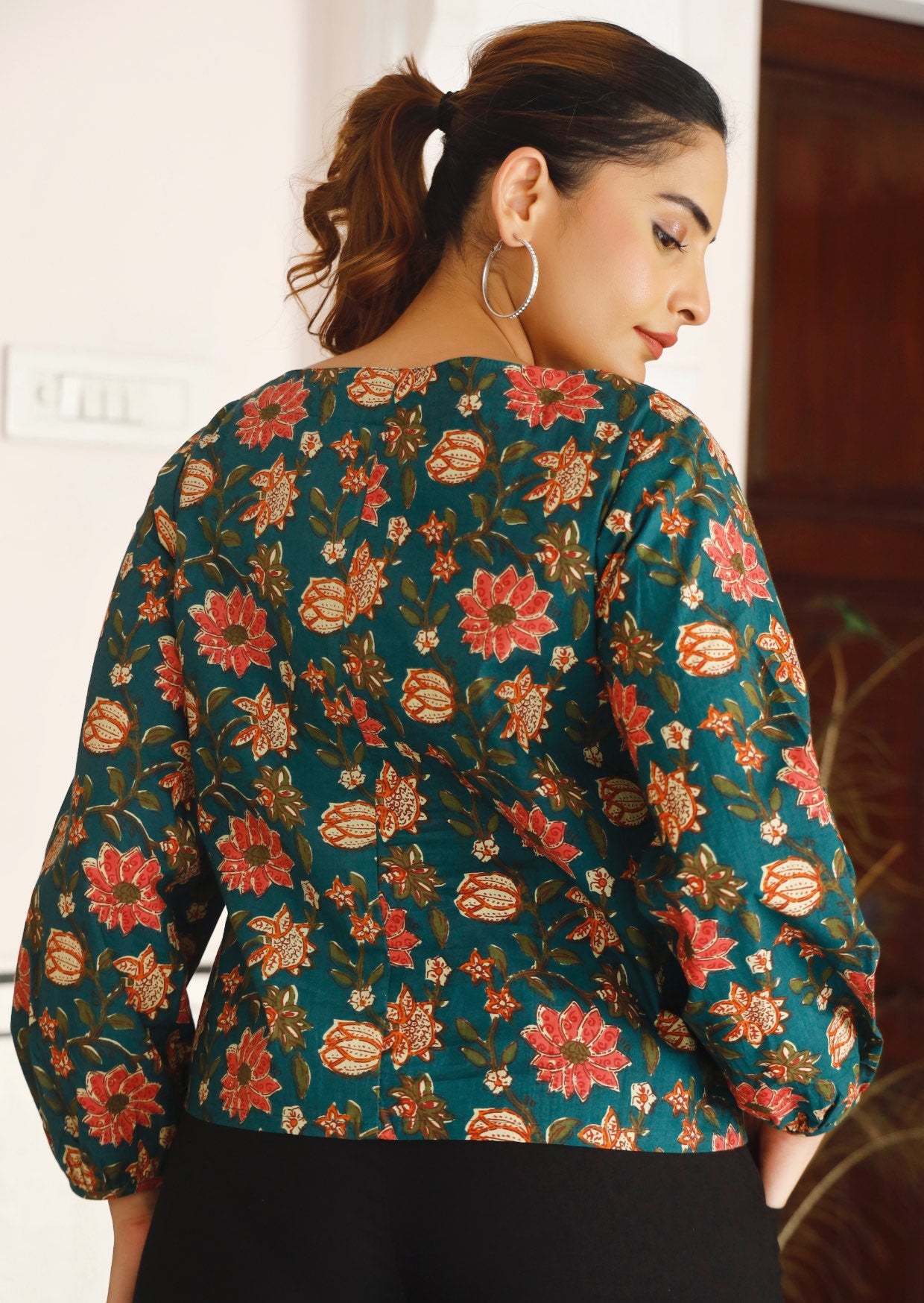 Model showing back of 100% cotton, loose fitting top with bishop sleeves and straight seam down the back