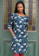 Woman wears cotton corduroy floral print dress with 3/4 sleeves with hands in pockets