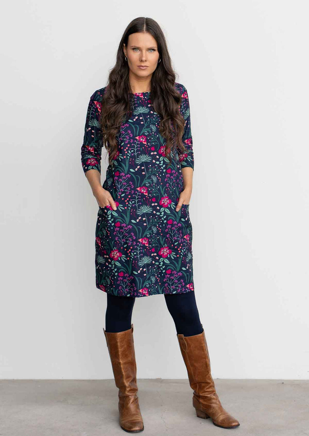 Woman wearing 100% cotton 3/4 sleeve navy shift dress with hands in pockets, navy leggings 