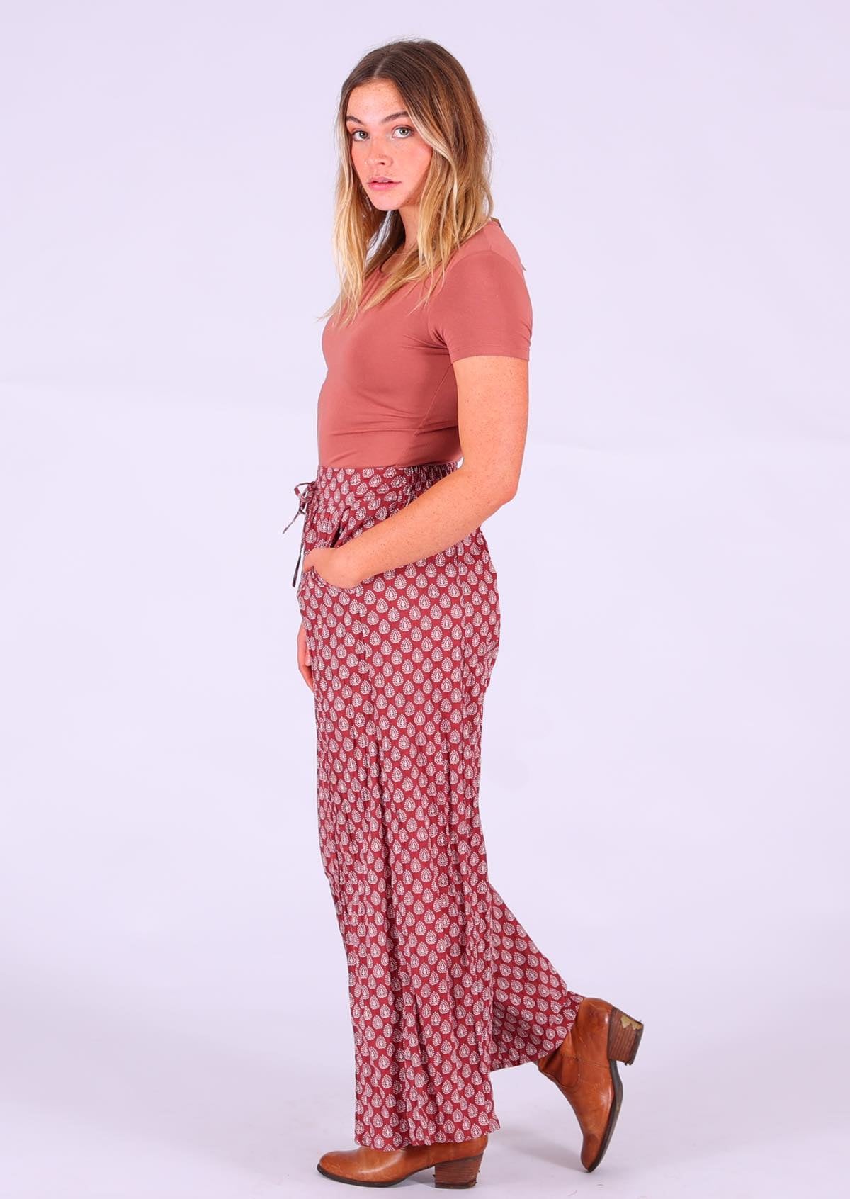 Model standing side on wearing Janis Pant Henna 100 percent cotton wide legged women's palazzo with hand in pocket