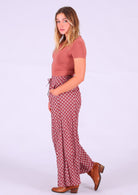 Model standing side on wearing Janis Pant Henna 100 percent cotton wide legged women's palazzo with hand in pocket