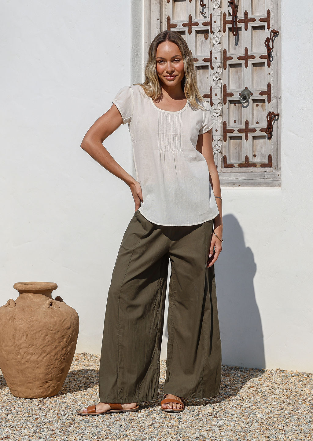 Woman poses in 100% cotton wide leg pants in olive green with drawstring waist tie and elastic back waist.