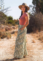 Woman stands in cotton wide leg pants paired with dust rose stretch rayon top, with hand in pocket