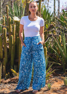 Model wears cotton wide leg pants in blue floral print with a stretch rayon white top, with her hands in the pockets