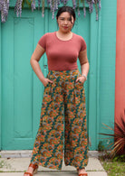 Model standing in front of aqua door with hands in pockets wearing rayon palazzo pant with pockets