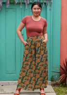 Model smiling standing in front of aqua door with hands in pockets wearing 100 percent rayon palazzo pant with pockets