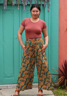 Model standing in front of aqua door with hands in pockets wearing 100 percent rayon palazzo pant with thumbs in pockets