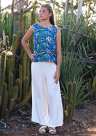 woman wearing wide legged white cotton pants and blue cotton top in front of cacti 