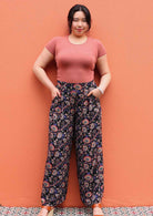 Model standing with hands in pocket wearing black and floral print 100 percent rayon womens palazzo pants