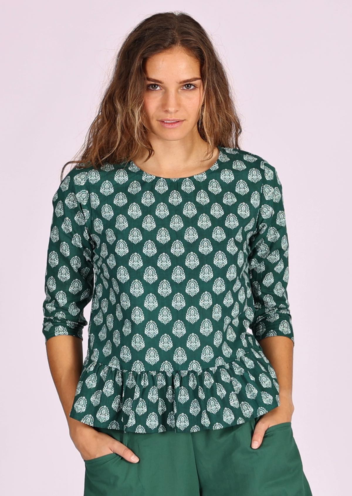 Simple sophistication in this white pendant print on dark green base peplum cotton top