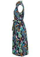 Side view of cap-sleeve button bodice cotton dress with a waist tie, collar and hidden side pockets, in a peacock and floral print on a dark navy base
