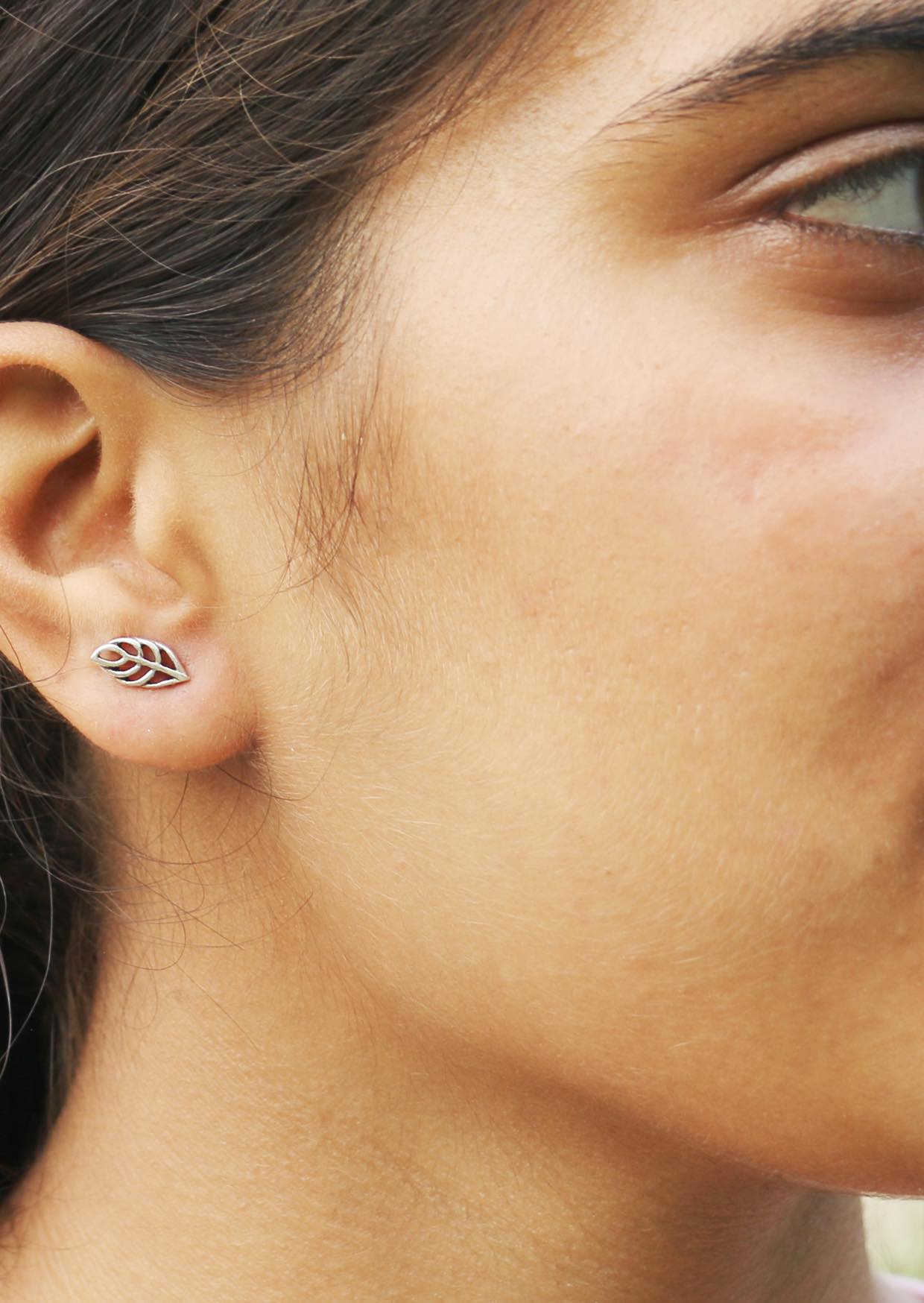 Close-up of a woman wearing a baeutiful silver leaf skeleton studs  