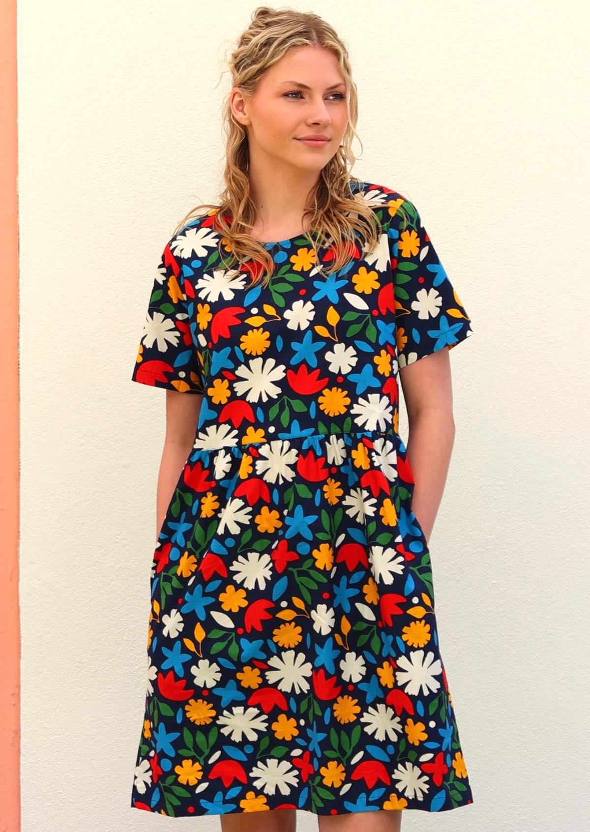 Model with blonde hair wearing 100 percent cotton dark navy blue base and bright abstract floral retro print cotton dress