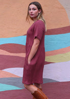 Model stands on side in 100% cotton above knee dress with t-shirt sleeves and pockets