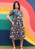 Woman poses in midi length cotton dress with short sleeves with thumb in hidden side pocket