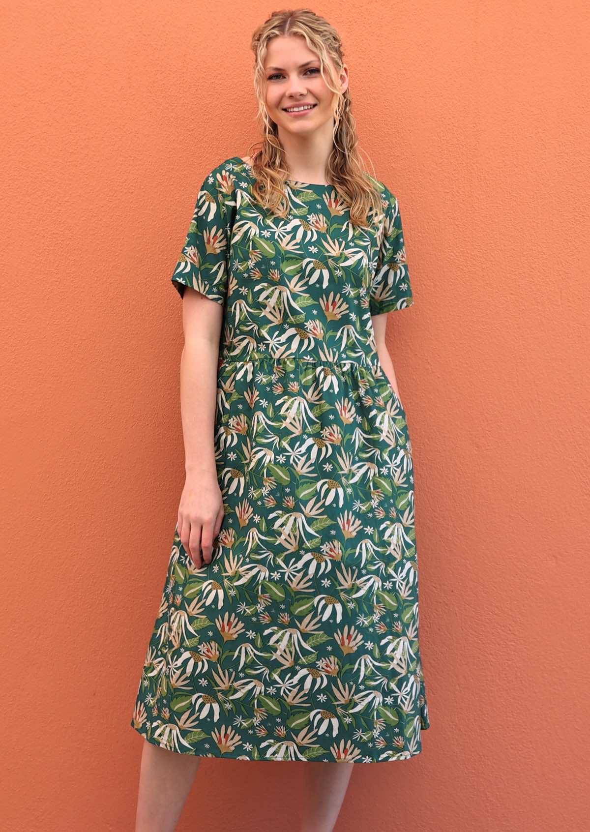 Model with one hand in pocket wearing 100 percent green cotton sundress with sleeves 