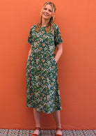 Model with hands in pockets wearing 100 percent green cotton sundress with sleeves 