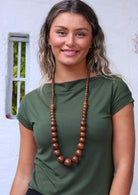 woman in green t-shirt with large dark wooden beads