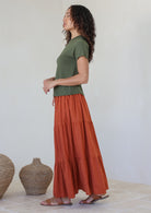 Model wearing a plain rust shade skirt with elasticated and drawstring waistband.