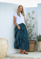 Model wearing a 100% cotton skirt in plain deep teal colour paired with a white top