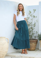 women wearing a 100% cotton deep teal skirt with a white plain top standing against a white background.