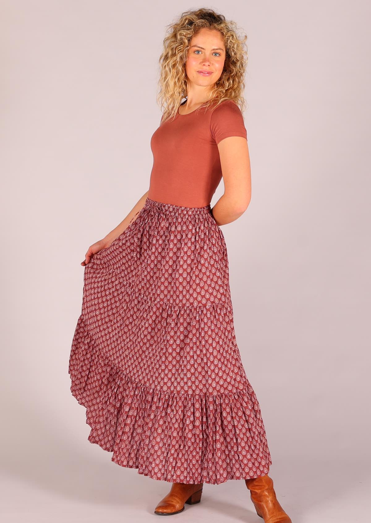 Model standing posing and wearing 100 percent cotton three tiered maxi skirt in dark terracotta 