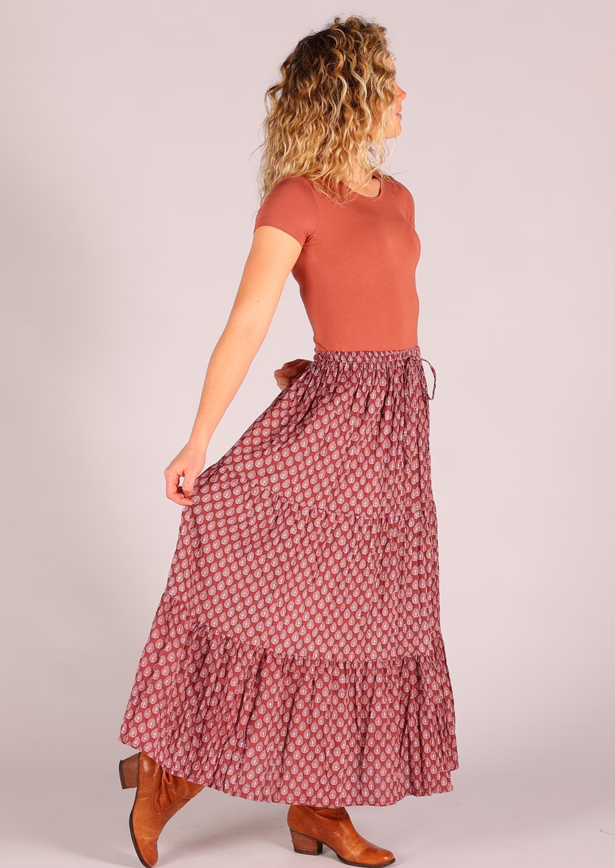 Model standing side on wearing 100 percent cotton three tiered maxi skirt in dark terracotta  