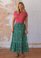 Woman wears 100% cotton maxi skirt with a drawstring in floral print on a jade green base