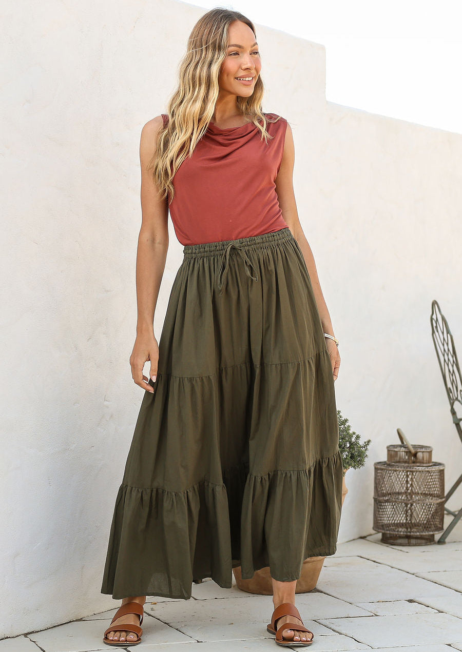 women wearing a 100% cotton olive green skirt with a pink plain top standing against a white background.