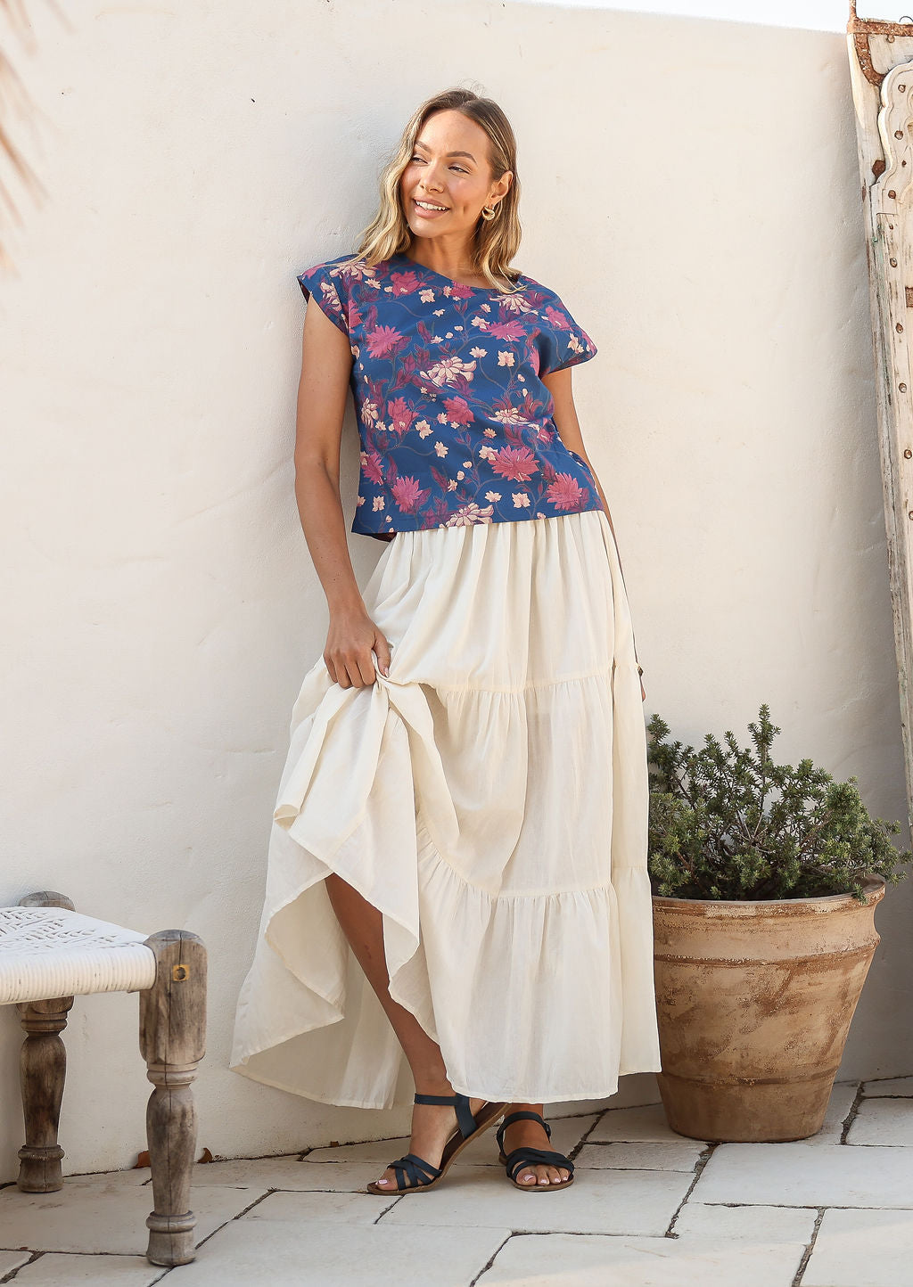 women wearing a 100% cotton white skirt with a blue printed top standing against a white background.