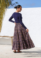 Model showcasing back of the cotton tiered maxi skirt in dark purple based sweet floral print.