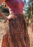 Close up of cotton maxi skirt with elastic waistband and shoestring tie, in warm toned print