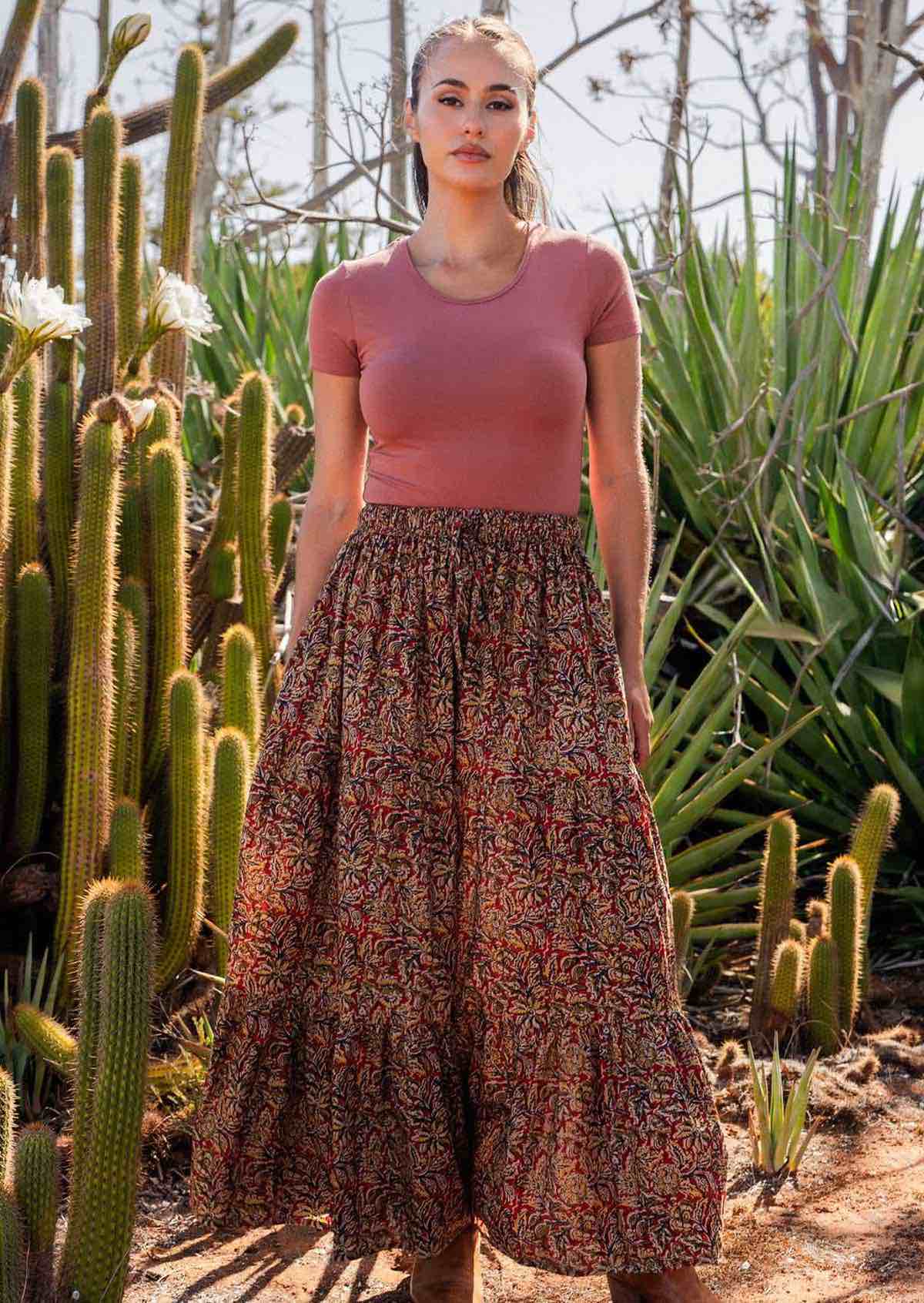 Woman wears cotton maxi tiered skirt with elastic waistband and drawstring, in warm toned floral print