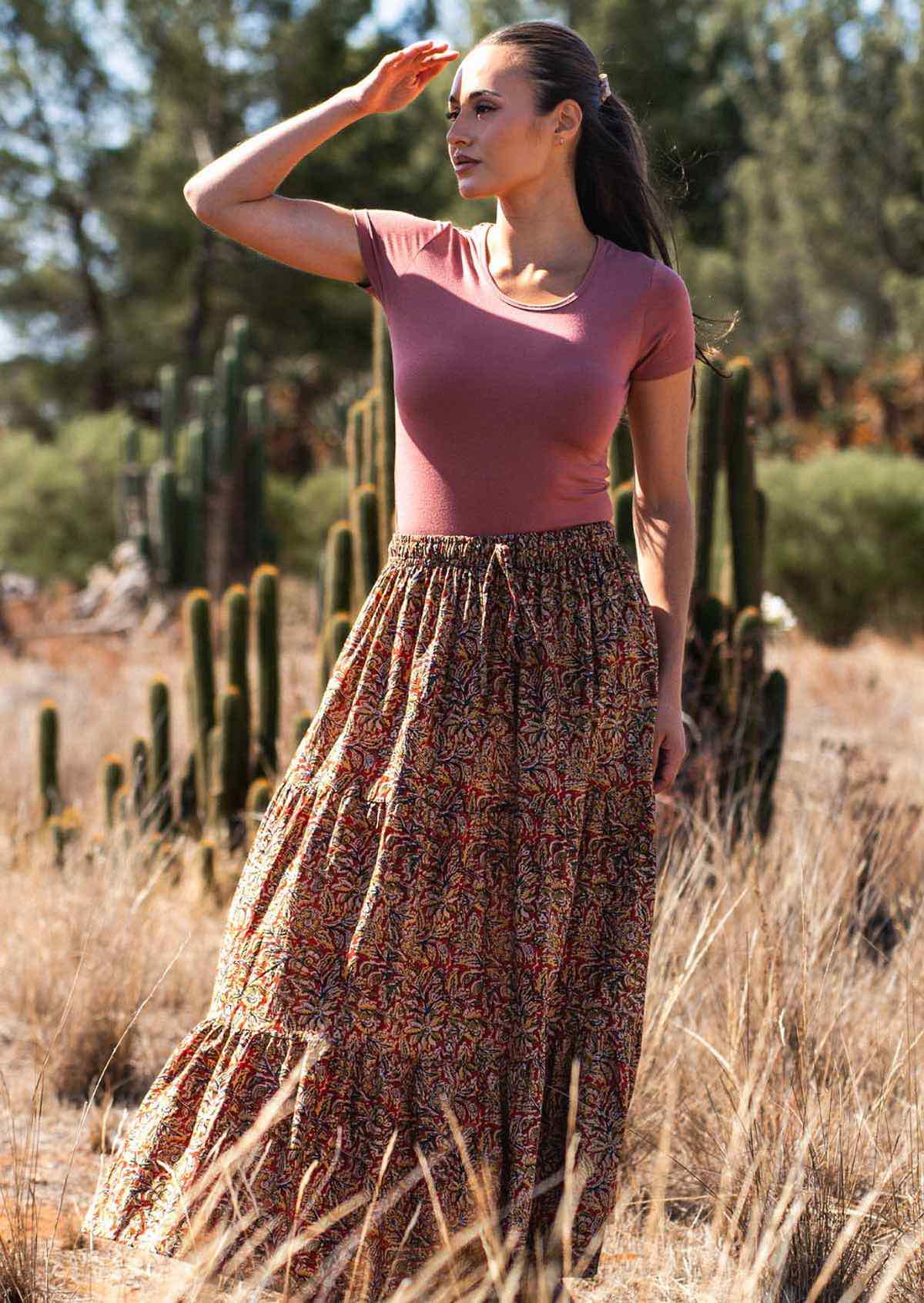 Woman wears cotton maxi skirt with tiers in warm toned print with dusty rose stretch rayon top